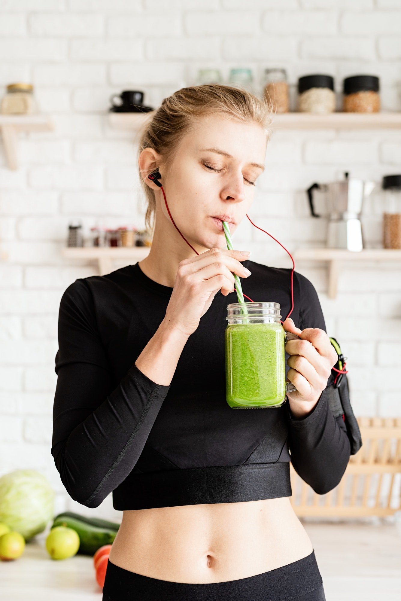 healthy-eating-dieting-concept-young-blond-woman-drinking-green-smoothie-from-mason-jar-at-home-ki.jpg